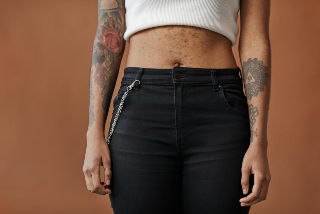 A fashionable look featuring tattoos and stylish black jeans, captured in a studio setting.